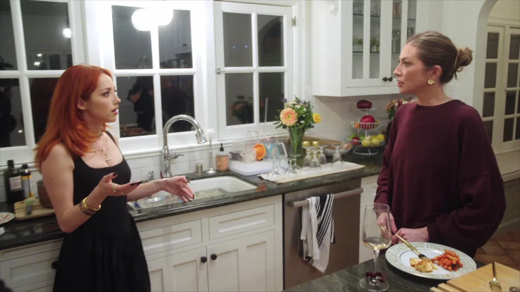 Georgiana Aubin and Stassi Schroeder Clark talking in a kitchen.