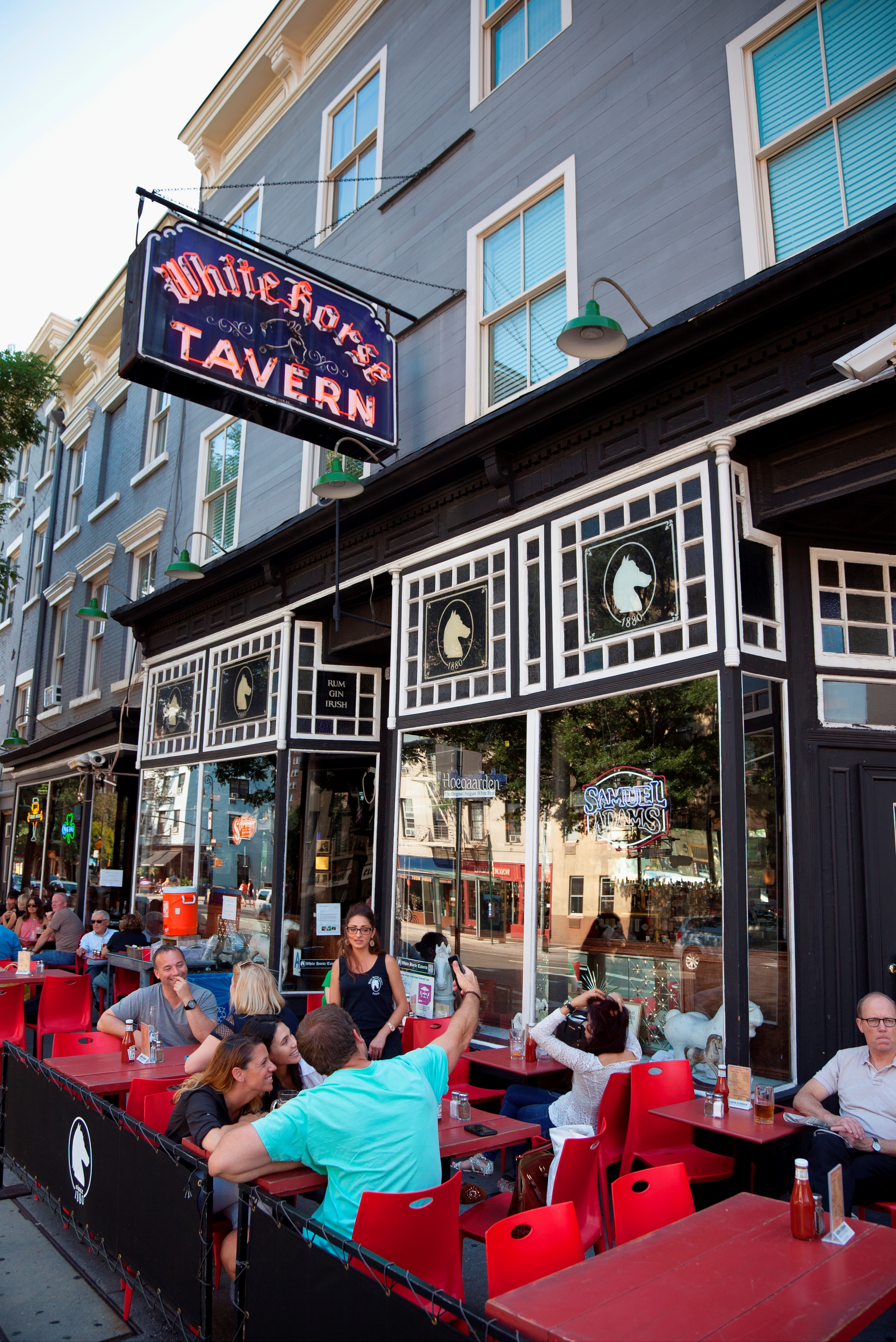 Exterior of the White Horse Tavern in Greenwich Village, New York City, with people seated at outdoor tables.