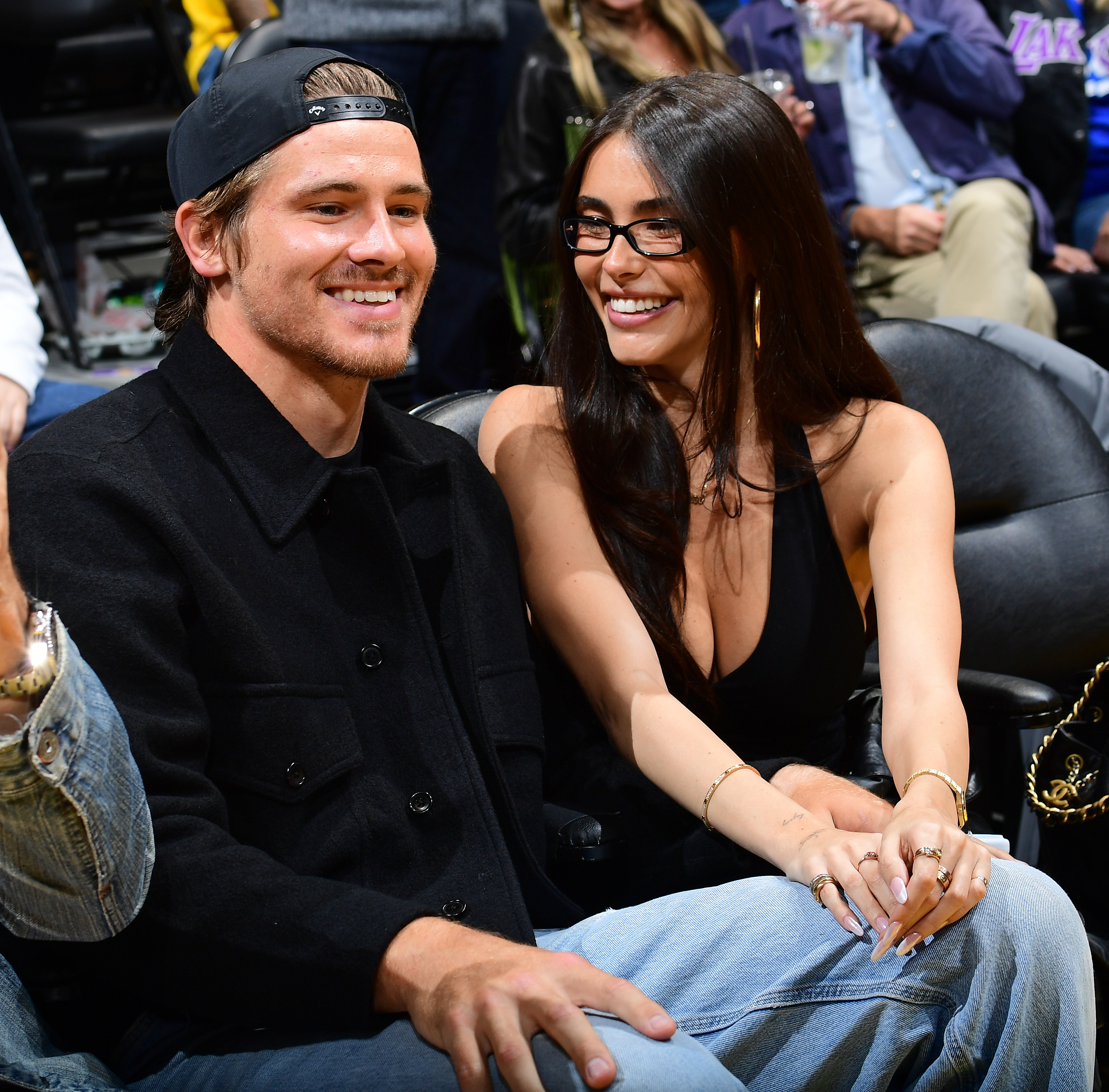 Justin Herbert and Madison Beer smiling at a basketball game.