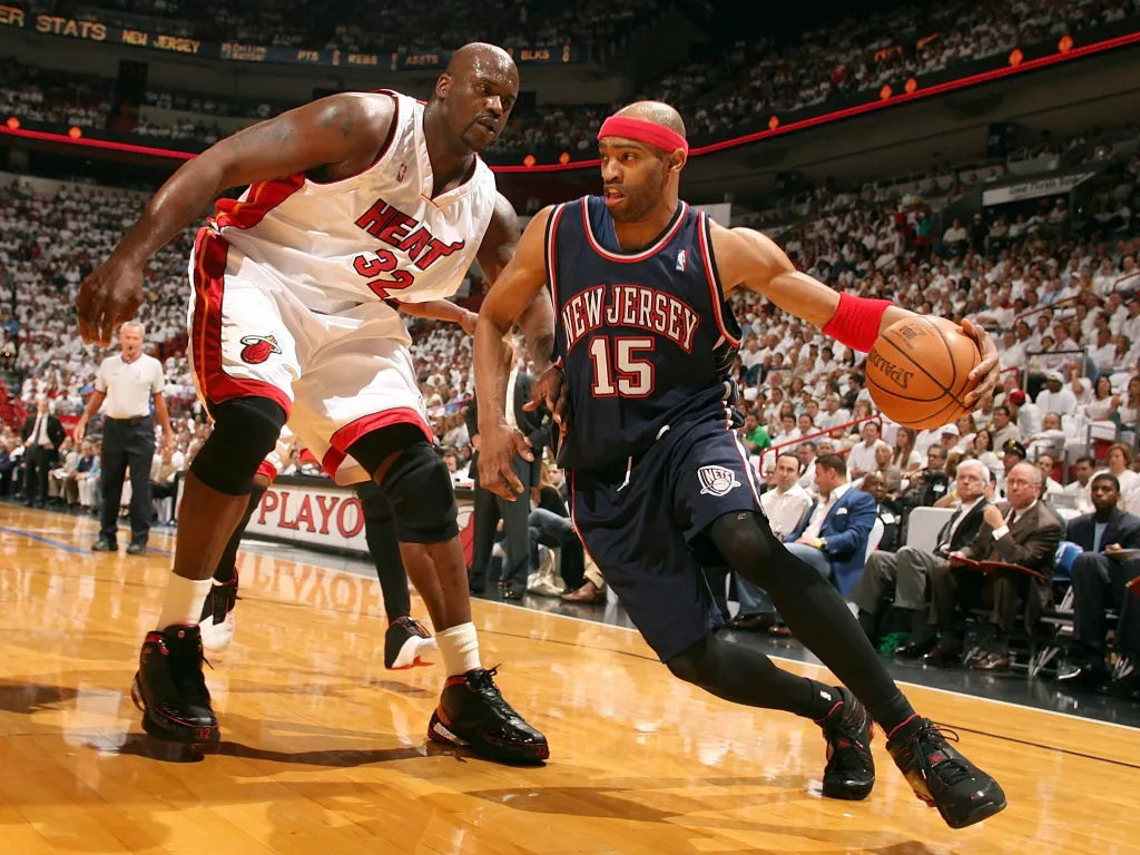 Vince Carter (New Jersey Nets) driving past Shaquille O'Neal (Miami Heat) during a basketball game.