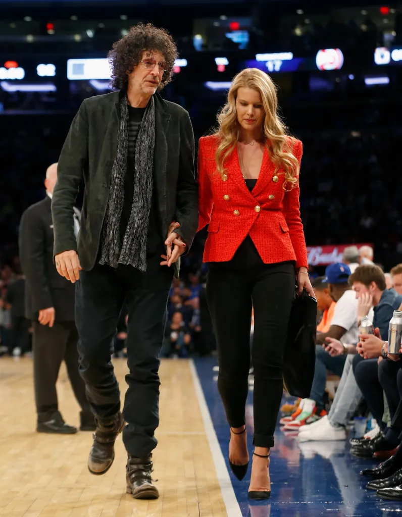 Howard Stern and Beth Ostrosky walking arm-in-arm at a basketball game.
