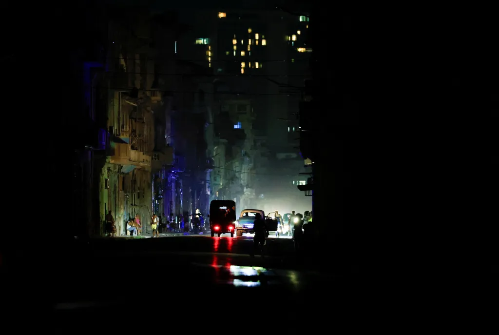 Vehicles drive down a dark street after Cuba's national electric grid collapsed.