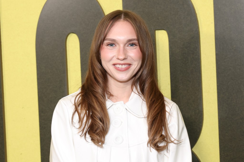 Veronika Slowikowska, in a white shirt, smiling at a premiere.