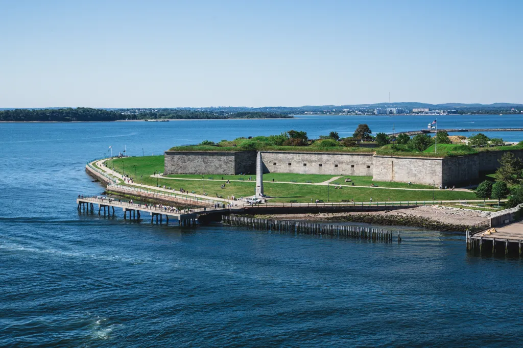 View of Fort Independence from the sea in Boston with a pier extending into the water.