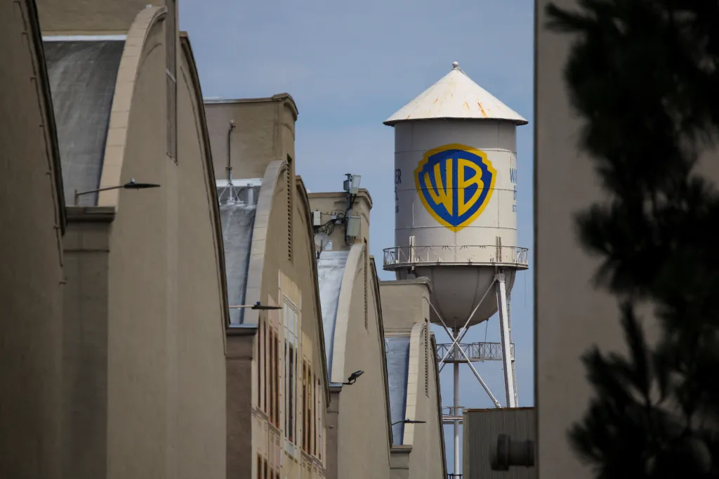 The Warner Bros. Water Tower with its blue and yellow WB logo, rising above studio buildings against a clear sky.
