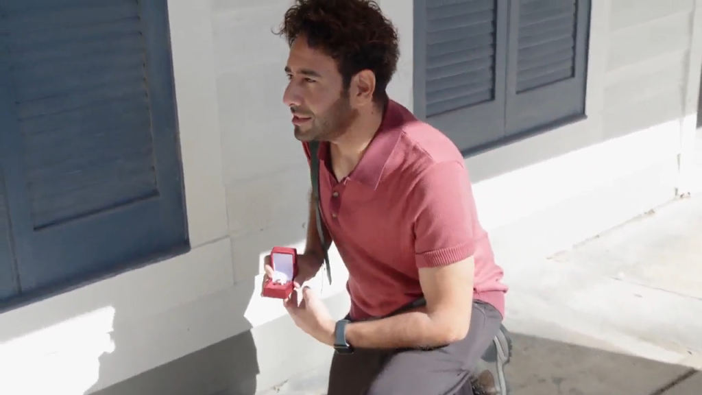 Man kneeling and holding an open ring box.