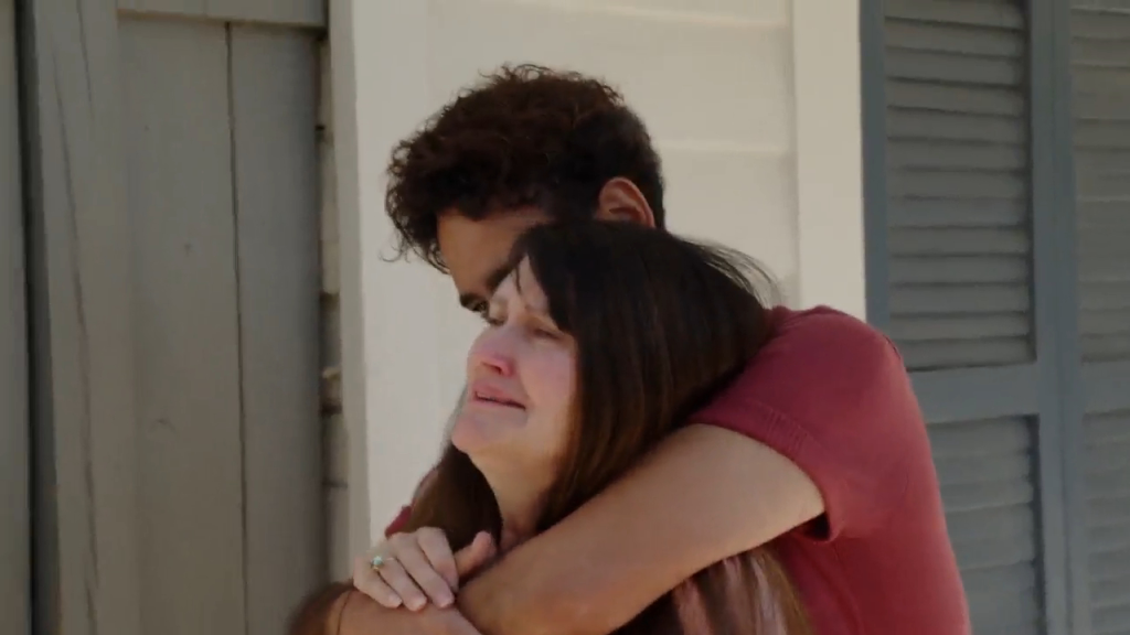 A woman, Debby, cries while a man, Mido, hugs her from behind.