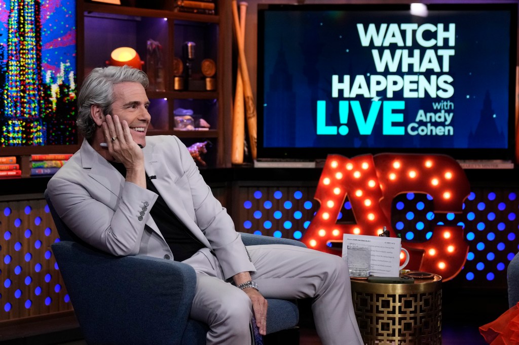 Andy Cohen smiling while seated in a chair on the set of "Watch What Happens Live."