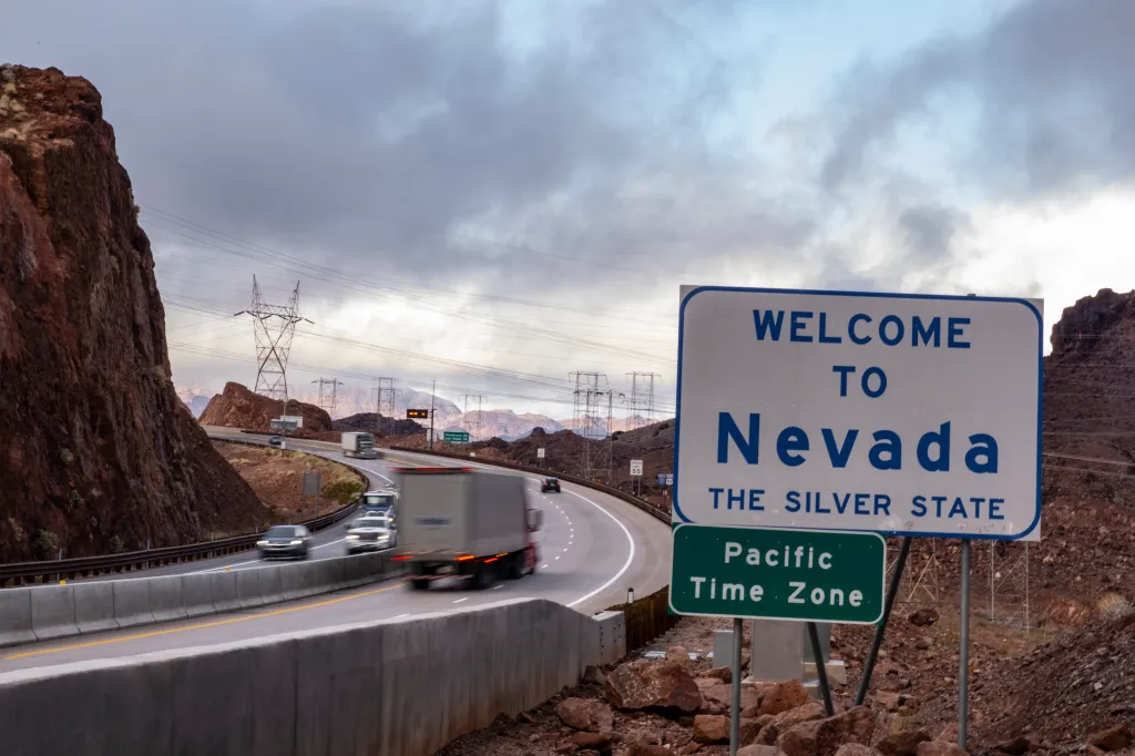 Welcome to Nevada sign with traffic.