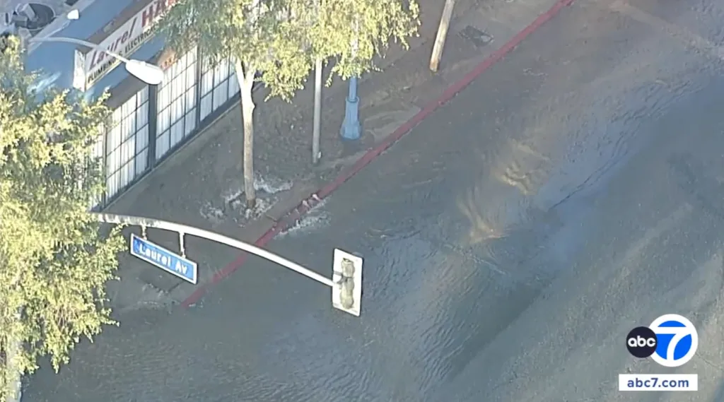 Aerial view of a flooded street, a traffic light, and a "Laurel Ave" street sign.