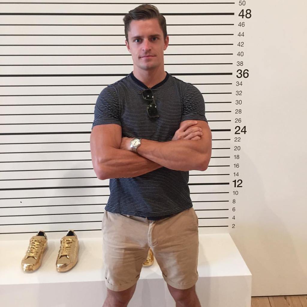 Kevin Sobieski standing in front of a white wall with horizontal black lines and numbers indicating measurement.