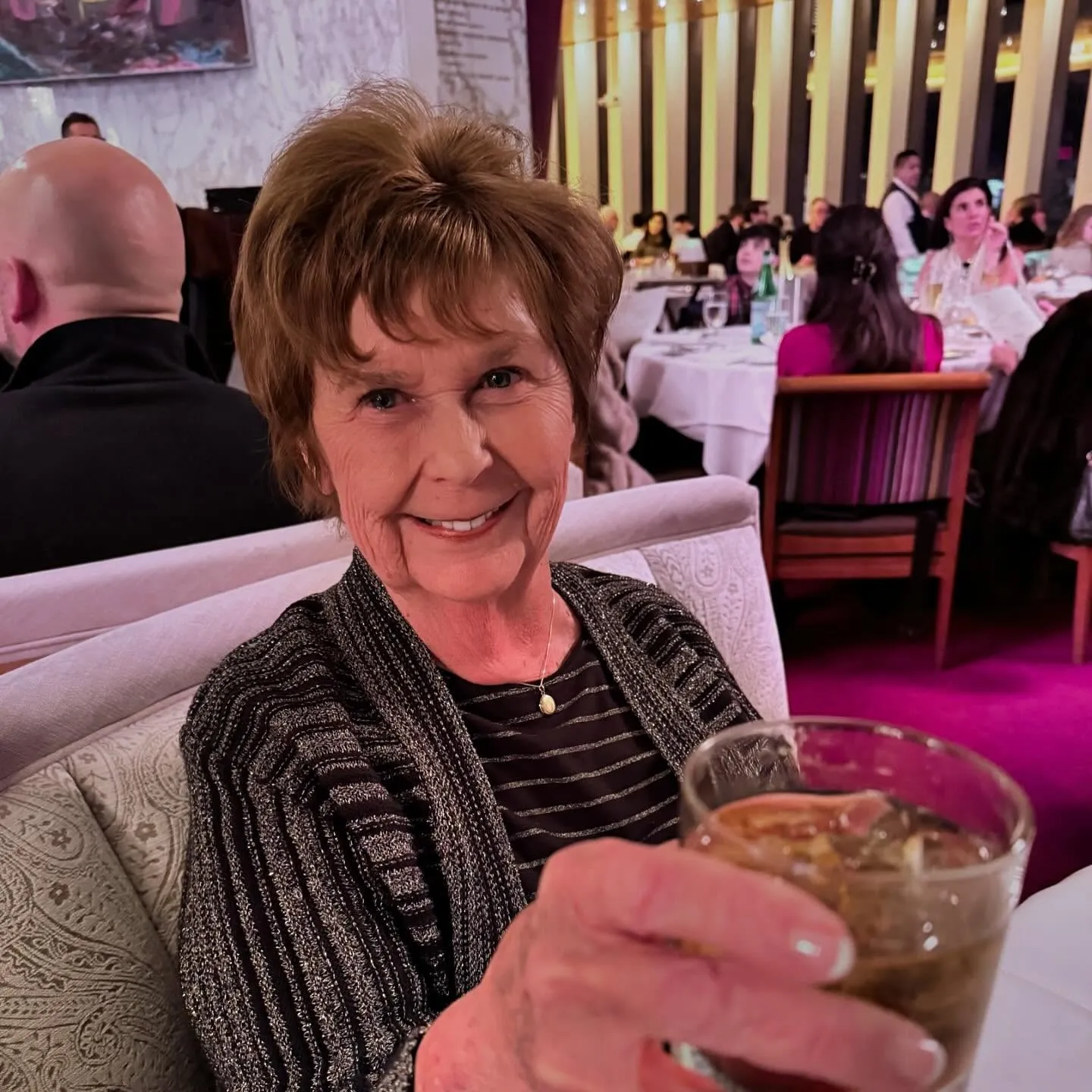 Nancy Guthrie smiling and holding a drink at a restaurant.