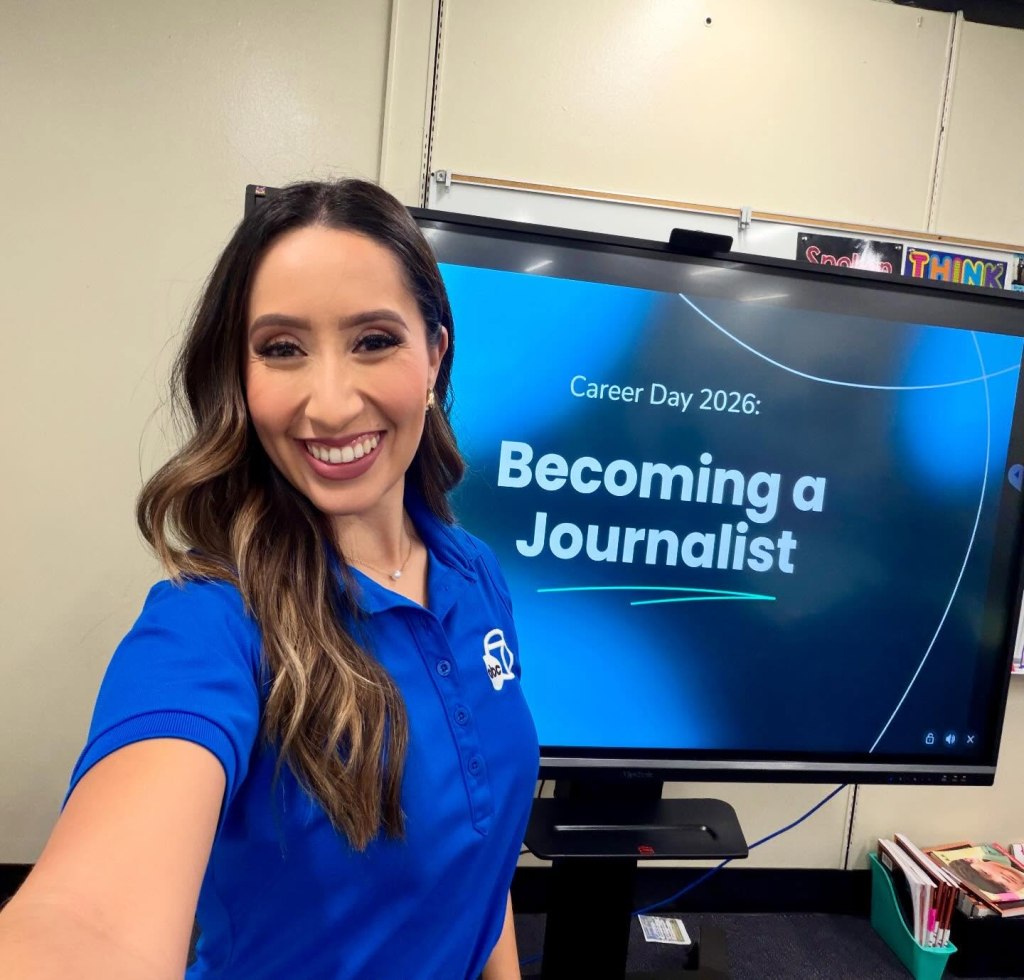 Mónica De Anda smiling in front of a screen displaying "Career Day 2026: Becoming a Journalist."