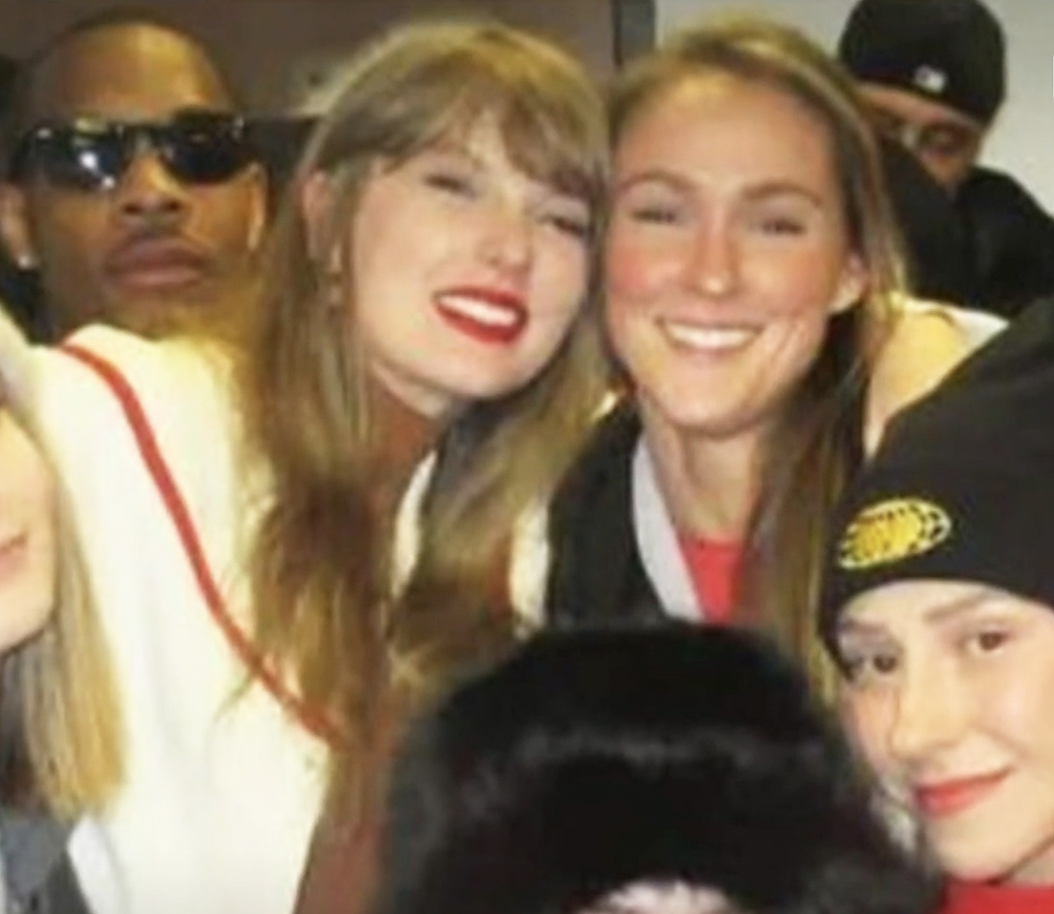 Taylor Swift and Kylie Kelce smiling with a group of people.