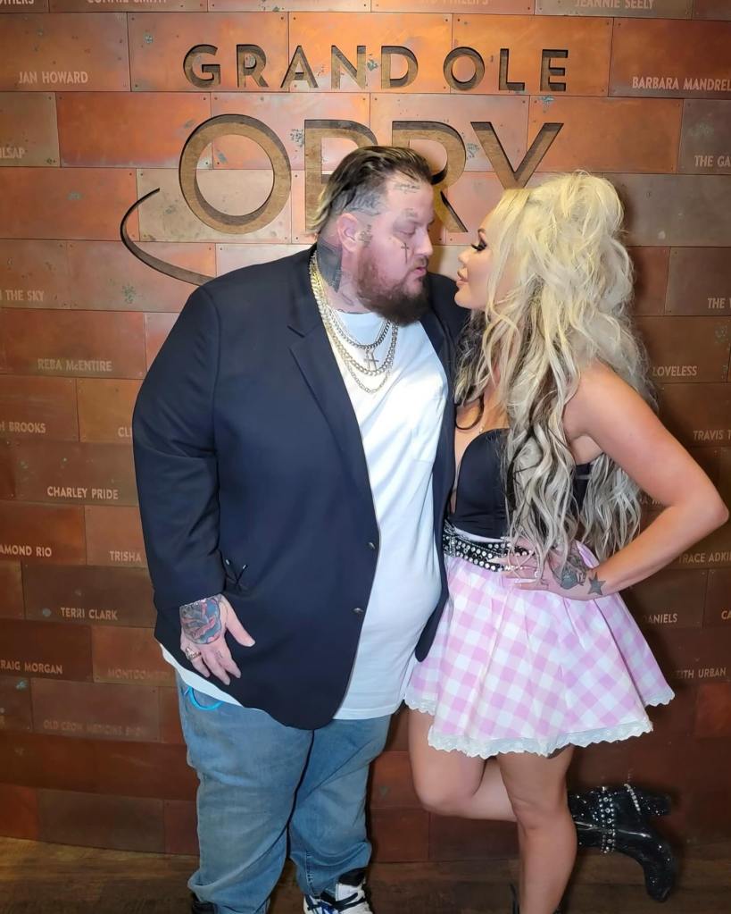 Bunnie XO and Jelly Roll posing together in front of the Grand Ole Opry wall.