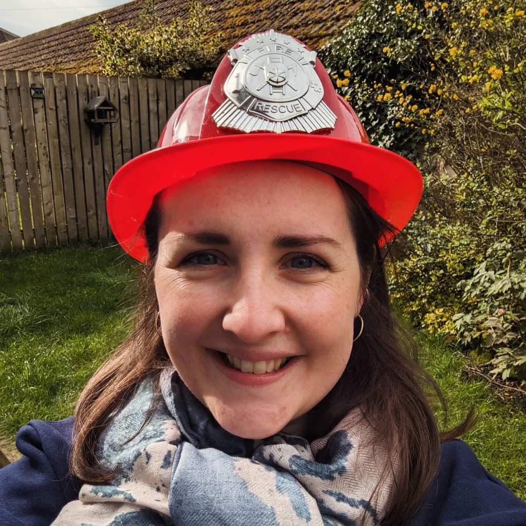 Theo Burrell smiling while wearing a red firefighter's helmet.