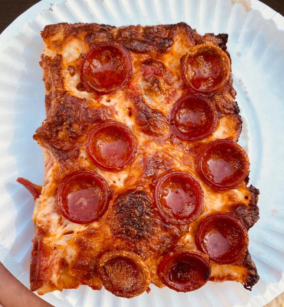 A square slice of pepperoni pizza with crispy edges on a paper plate.