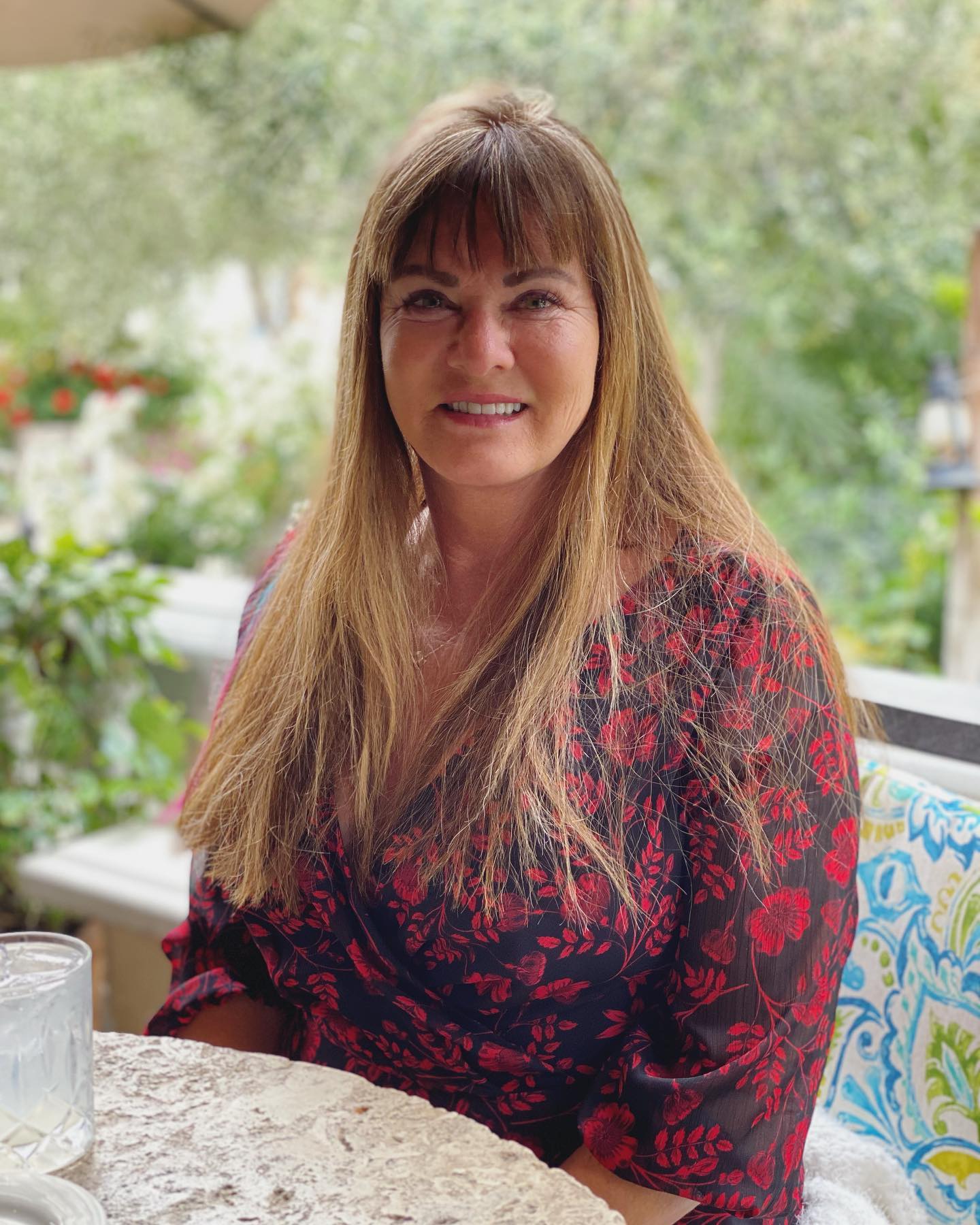 Jeana Keough smiling while sitting at a table outdoors.