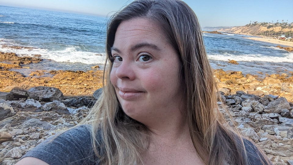 Reality TV star Cristina Sanz smiling at a rocky beach.