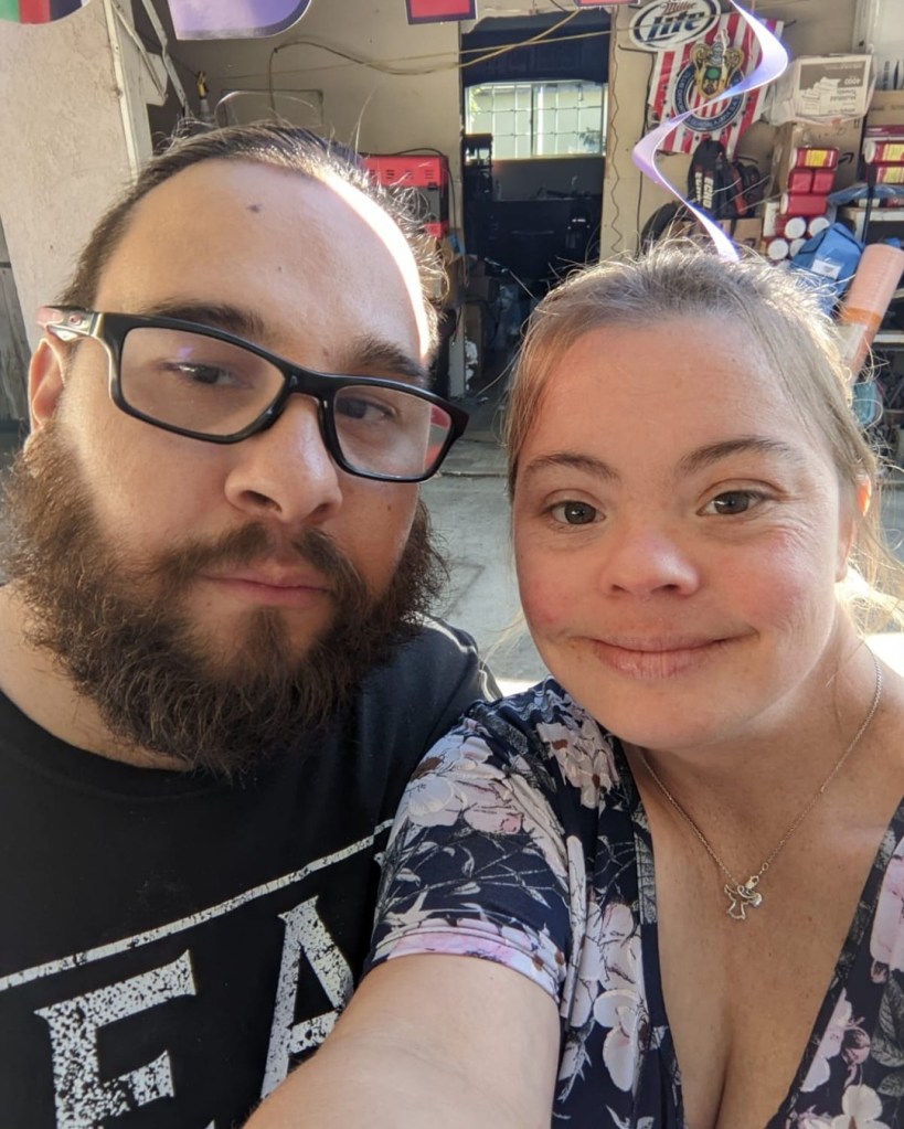 Reality TV star Cristina Sanz smiling next to a man with a beard and glasses.
