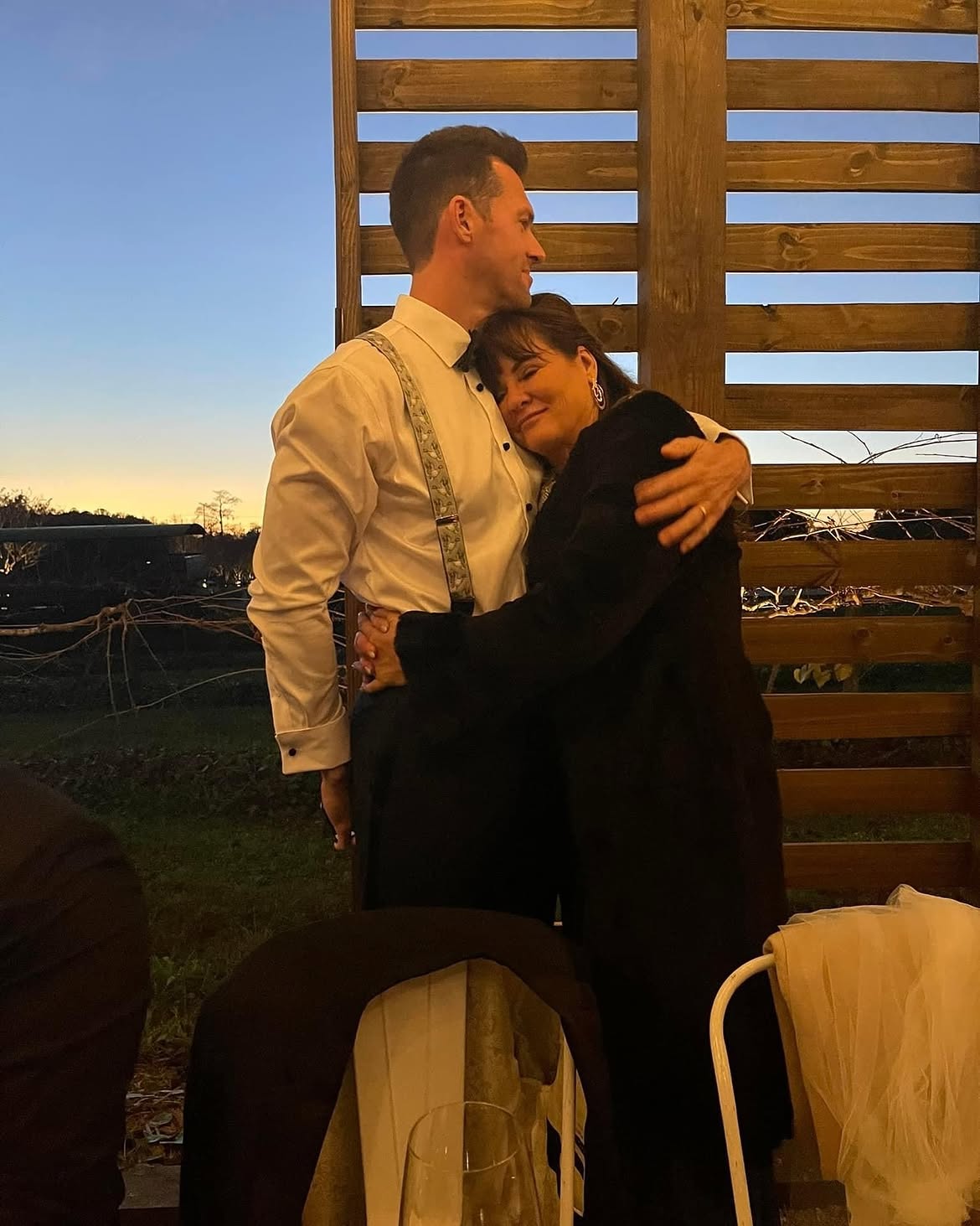 Jeana Keough embracing her son Shane against a wooden fence.