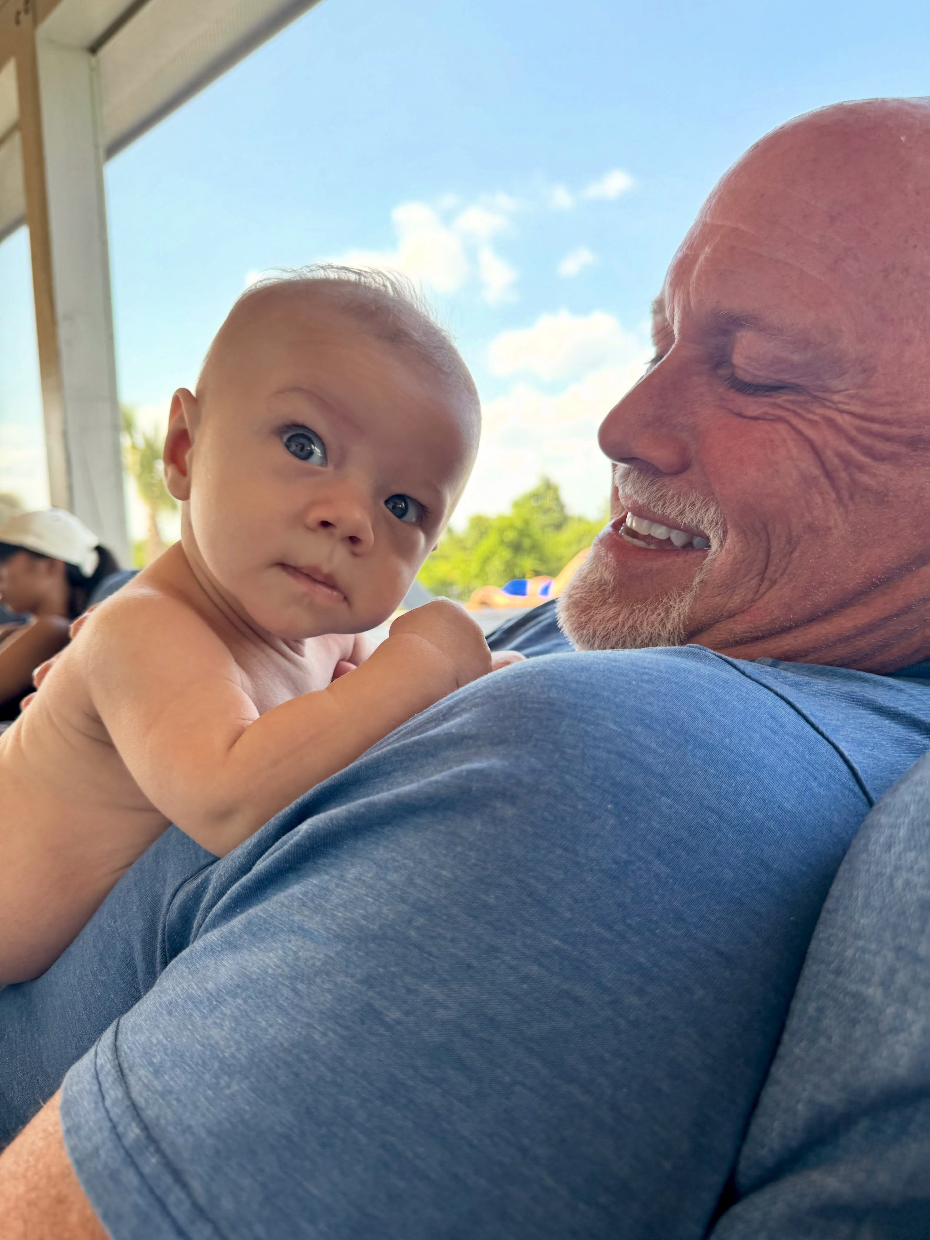 A baby looking over an older man's shoulder.