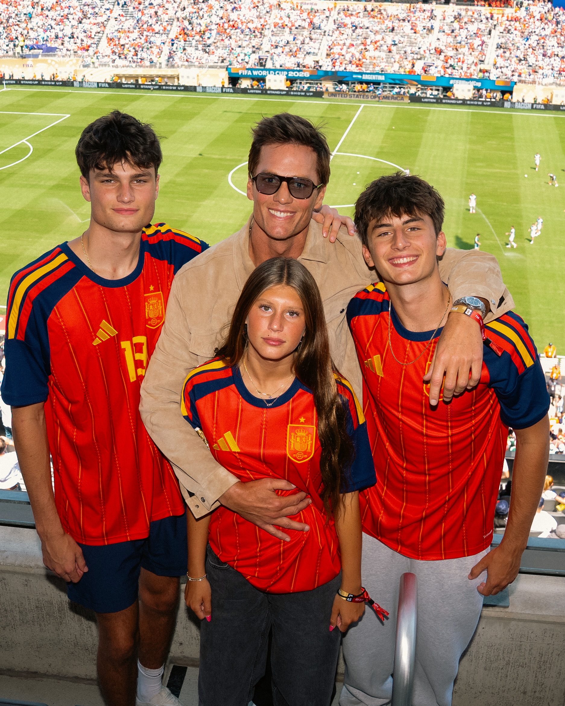Tom Brady with three children in red soccer jerseys at the World Cup.