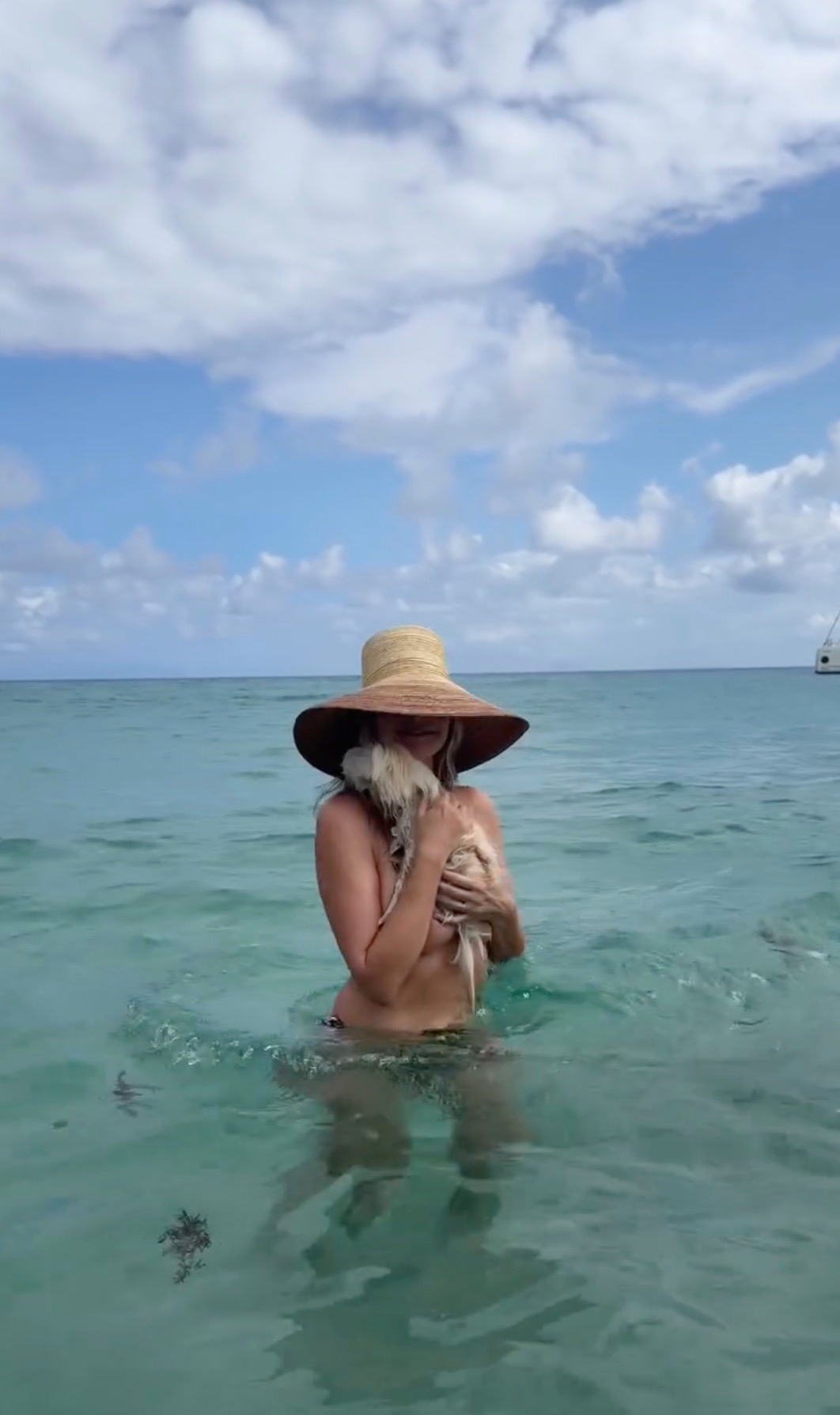 Heidi Klum in the ocean without a bikini top, holding her dog.