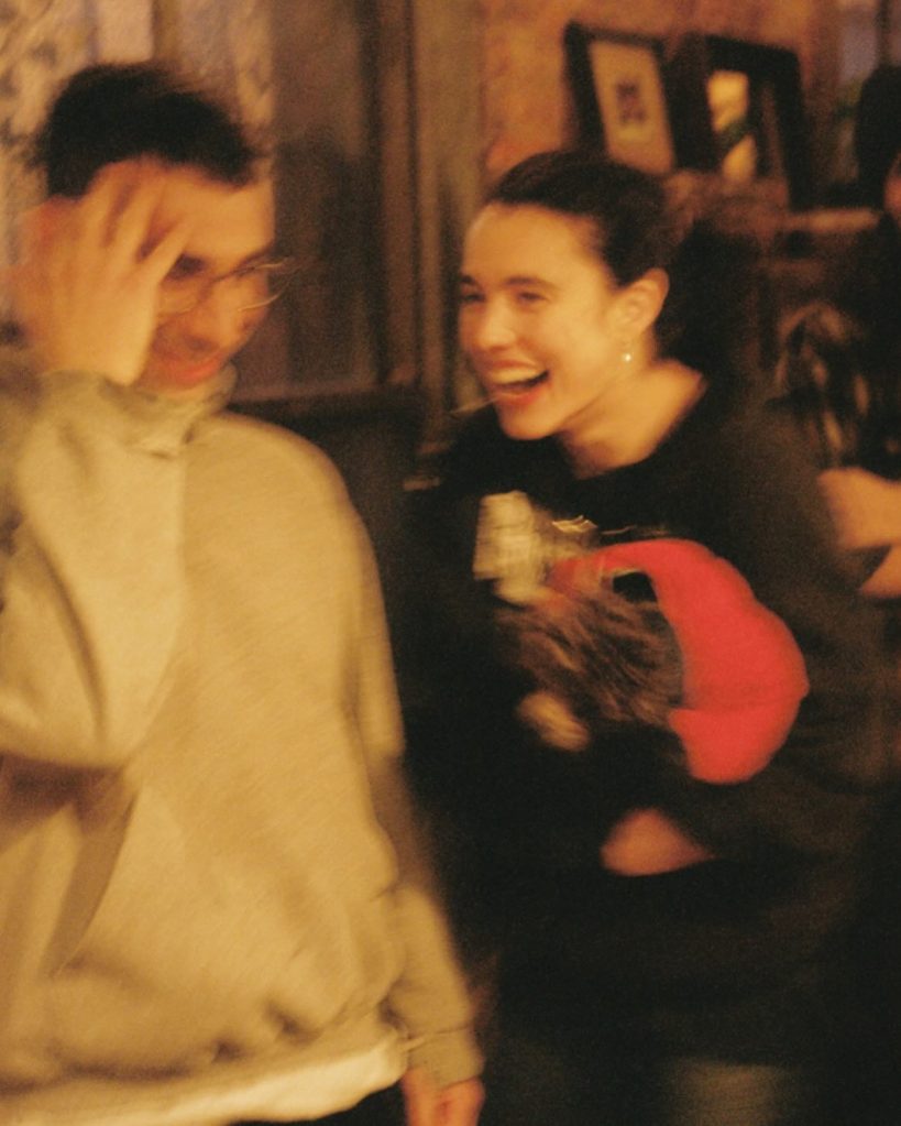Two people laughing and talking, the one on the right smiling widely.