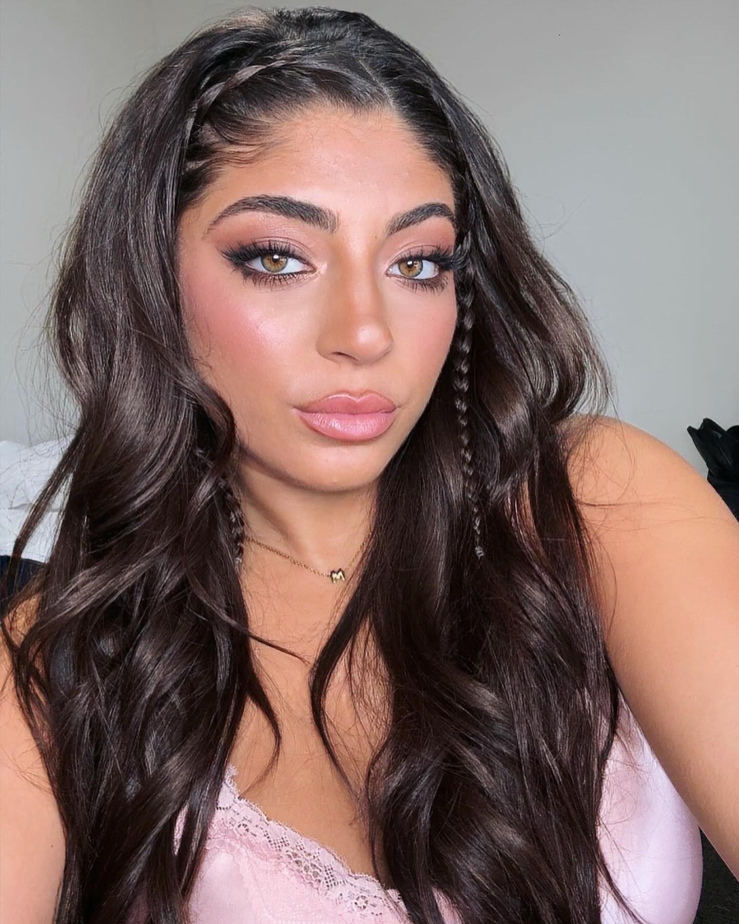 Milania Giudice wearing a pink top with long wavy dark hair and two small braids, with full makeup.