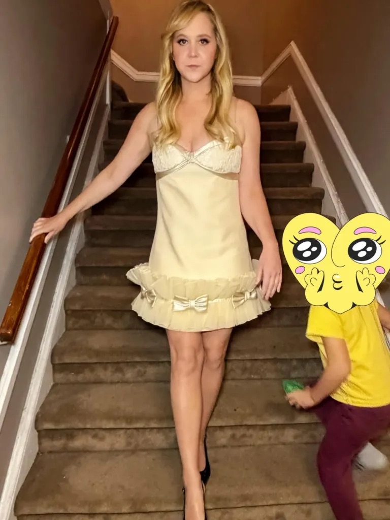 Amy Schumer posing in a skimpy dress on a staircase with her son.