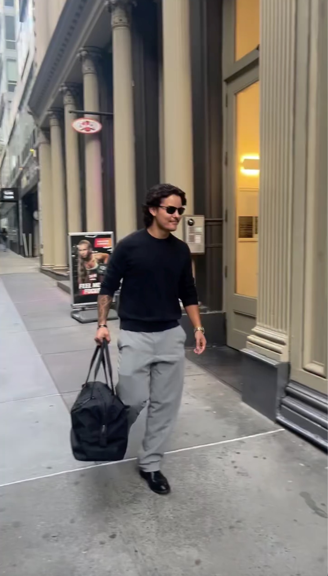 Collin Gosselin walking down a city sidewalk with a black duffle bag.