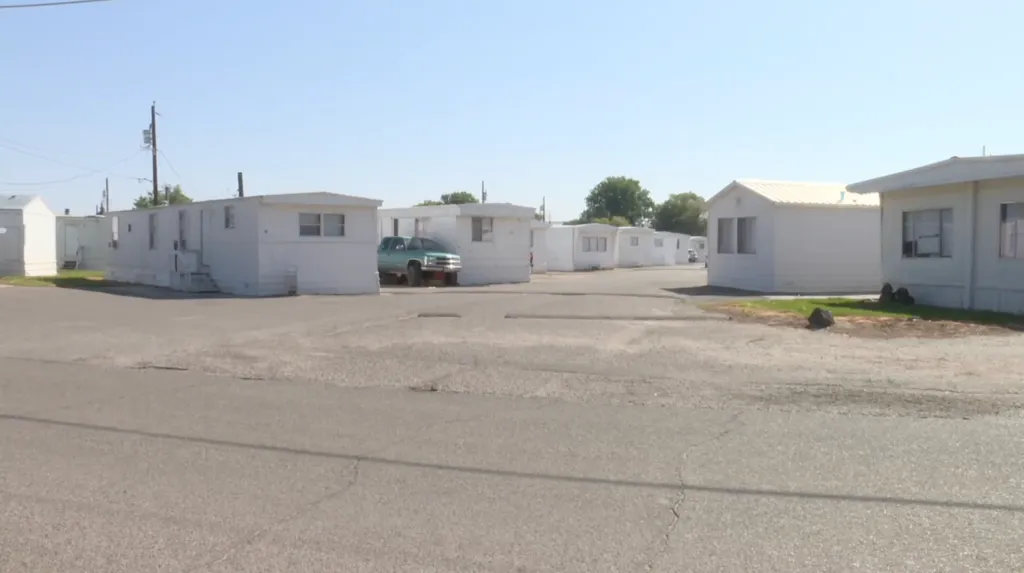 A street winding through a trailer park with multiple white mobile homes.
