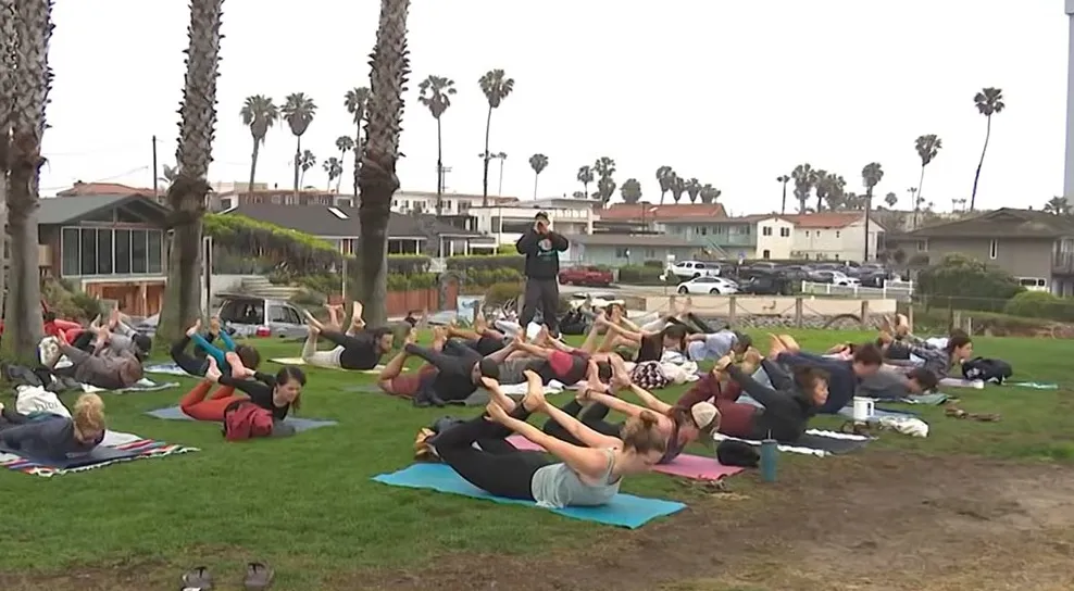 People practicing yoga outdoors with an instructor.
