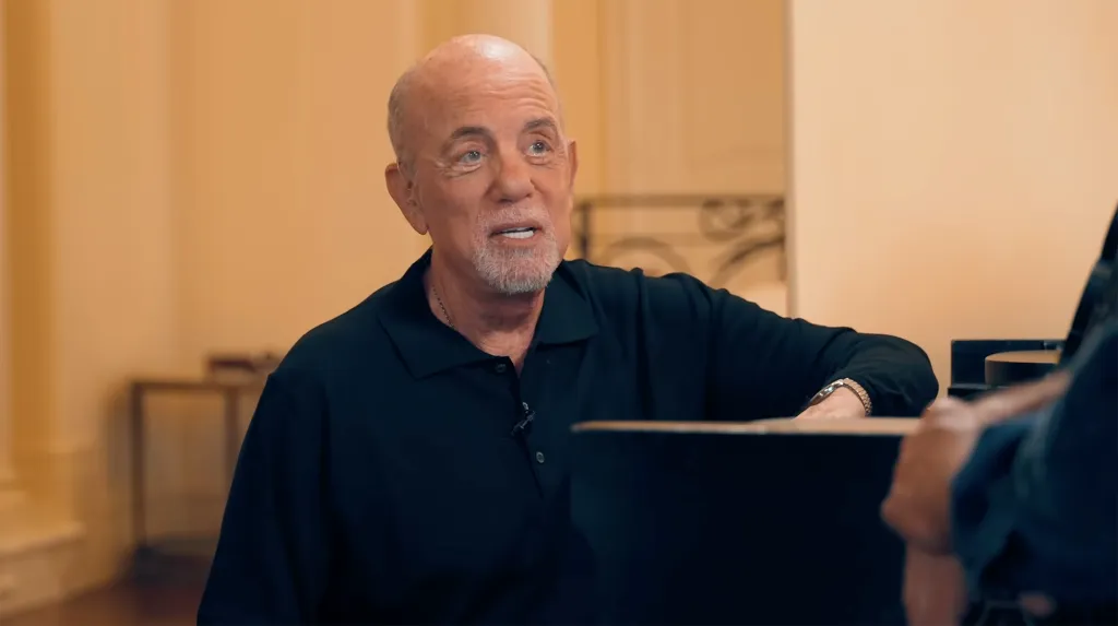 Billy Joel in a black polo shirt.