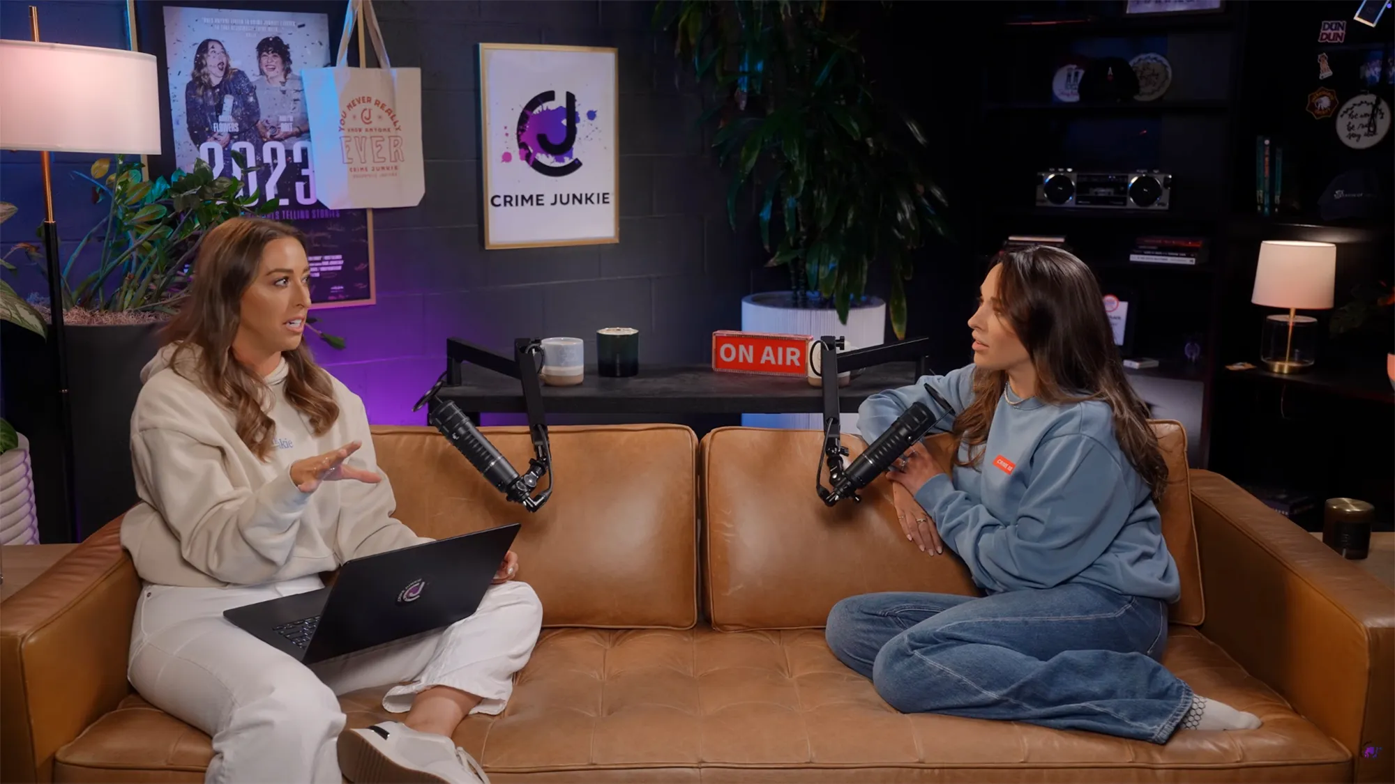 Two women recording the Crime Junkie podcast with "ON AIR" sign on the table.