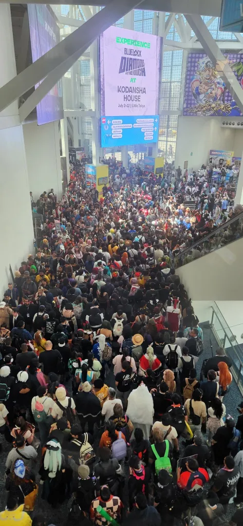 An extremely crowded Anime Expo hall filled with attendees, many in costumes.