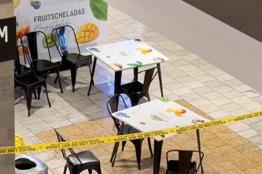 Yellow police tape cordons off tables and chairs near a smoothie bowl sign in a mall food court.