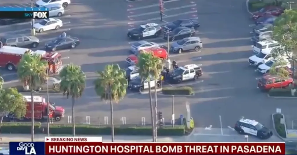 Aerial view of a hospital parking lot with police cars, fire trucks, and ambulances responding to a bomb threat.