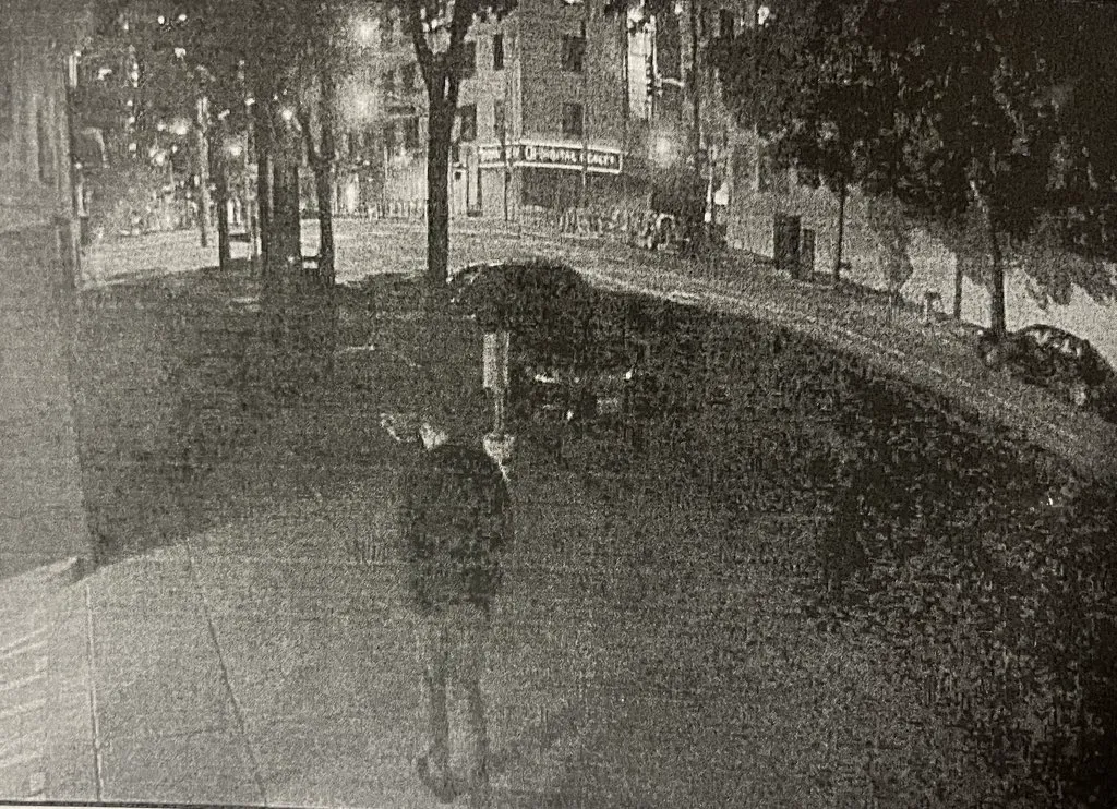 A grainy, black and white security camera photo shows Bob Lee walking on a sidewalk at night, with streetlights and buildings in the background.