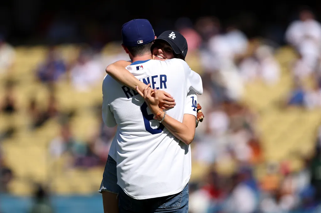 Romy Reiner and Jake Reiner hug after throwing the ceremonial first pitch at Dodger Stadium.