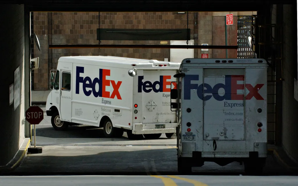 A FedEx employee holds a package in a FedEx facility.