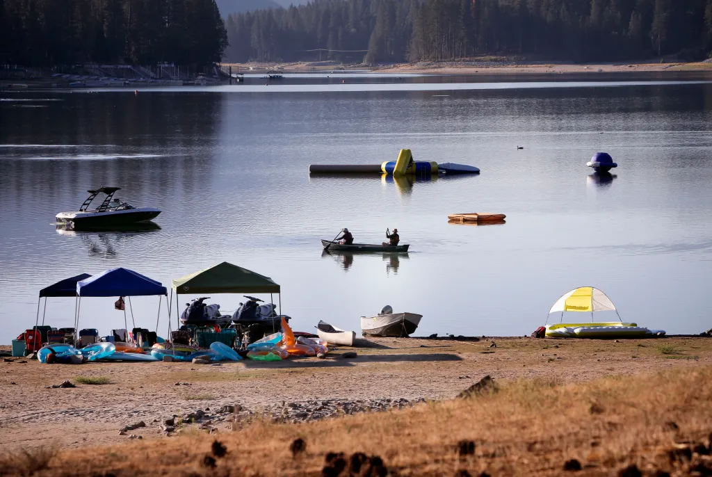 Boats and water toys docked on a lake's shoreline due to low water levels from a prolonged drought.