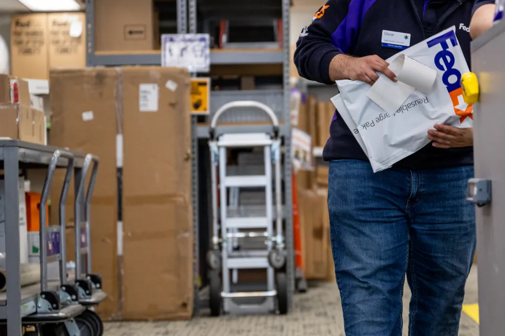 A FedEx employee holds a package in a FedEx facility.