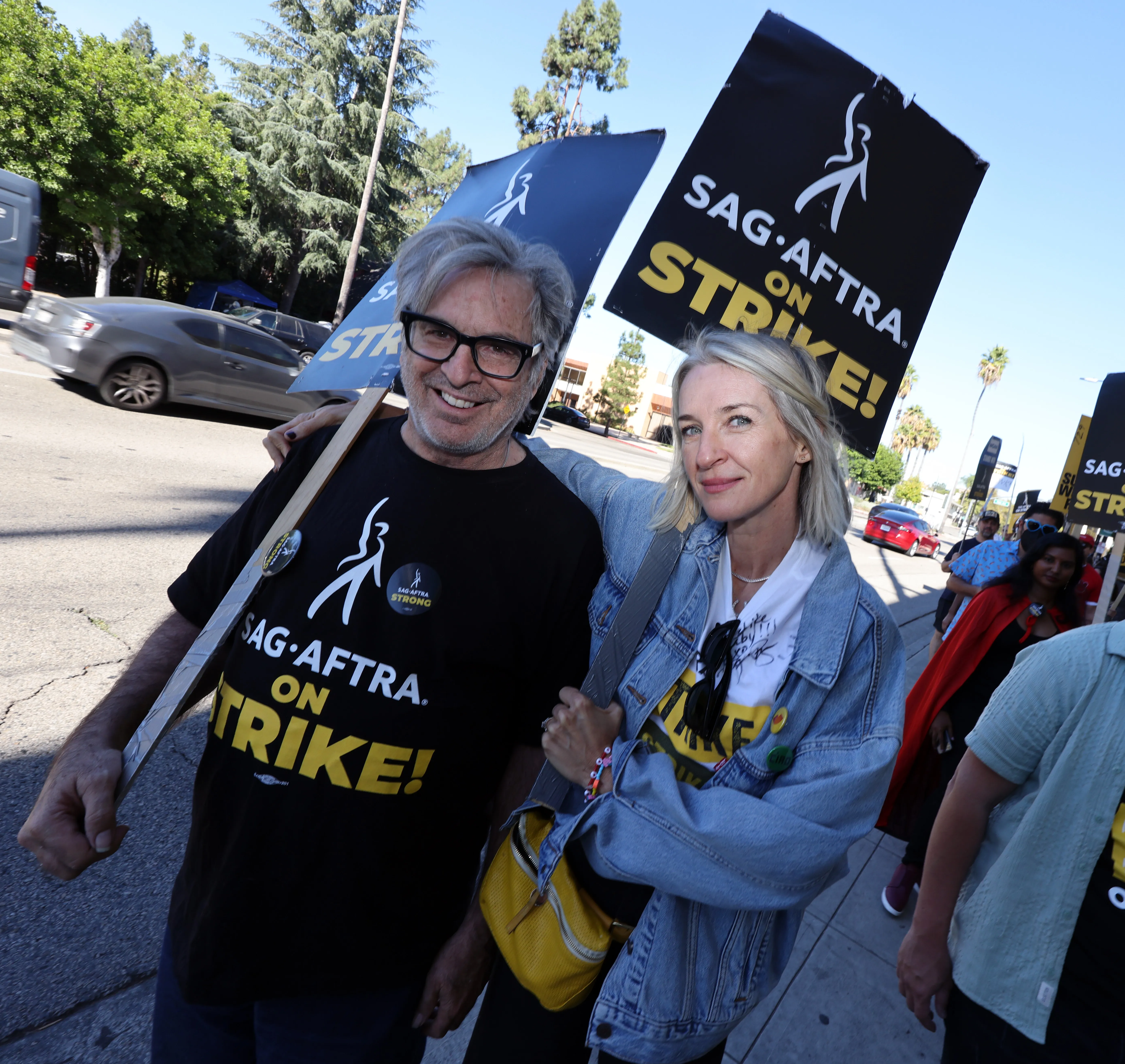 Robert Carradine and Ever Carradine holding "SAG-AFTRA ON STRIKE!" signs during the SAG-AFTRA strike.