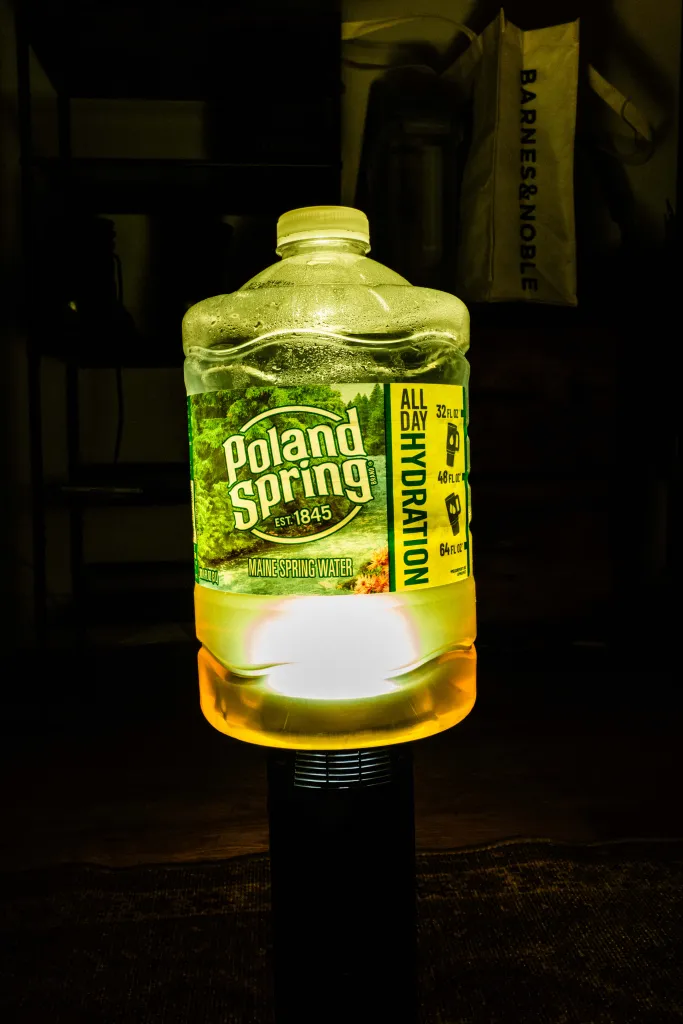 A Poland Spring water bottle illuminated from below, with a Barnes & Noble bag in the background.