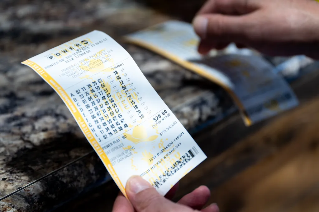 A person holding several Powerball lottery tickets.