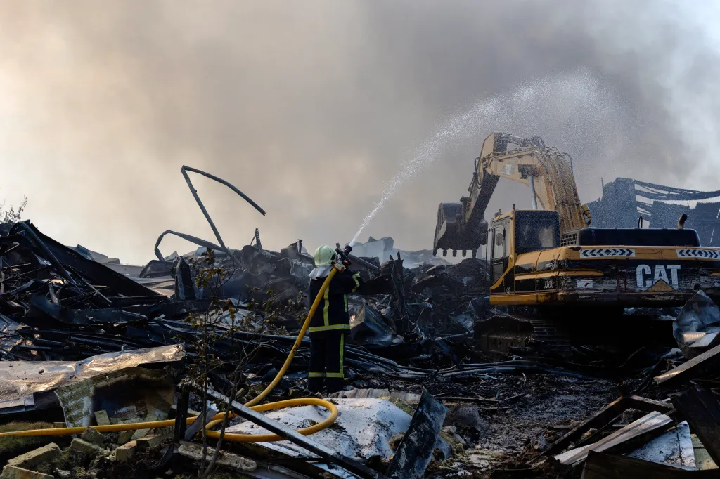 A Ukrainian firefighter sprays water on the smoldering debris of a building hit by a Russian missile.