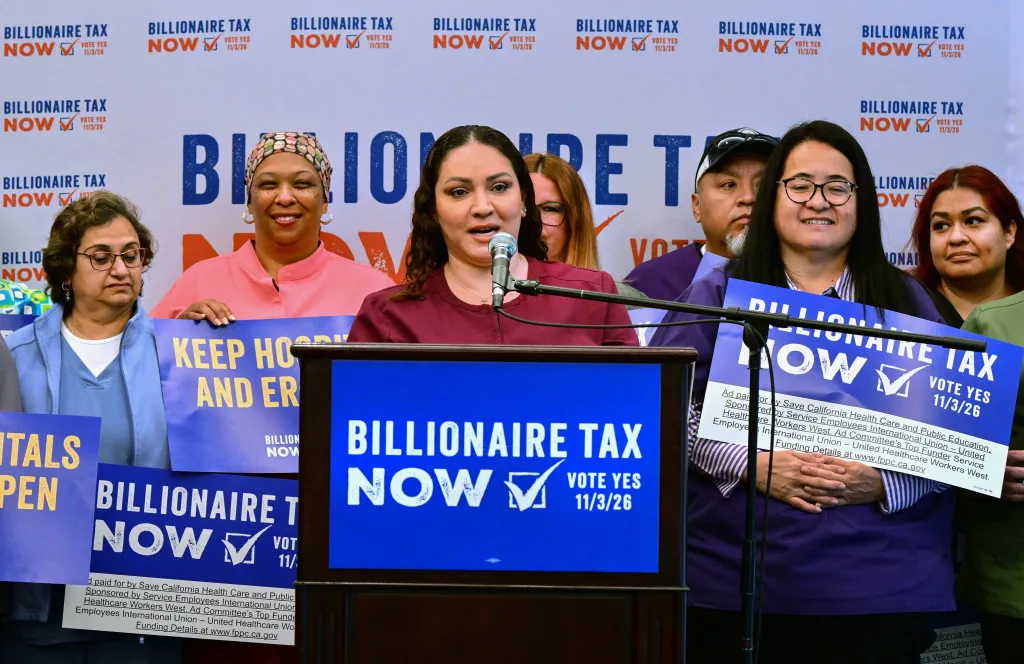Ultrasound Technologist Mayra Castaneda speaks in front of healthcare workers holding placards supporting the Billionaire Tax.