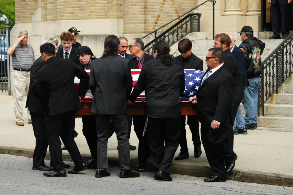 Pallbearers, including Stevie Van Zandt, carry Vincent Pastore's casket draped in an American flag during his funeral.